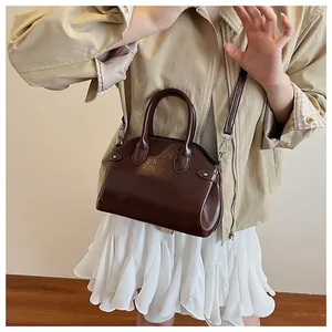 Détail d'un sac à main marron brillant avec poignées et bandoulière réglable amovible
