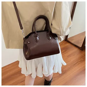 Détail d'un élégant sac coquille en cuir marron foncé avec poignée et bandoulière
