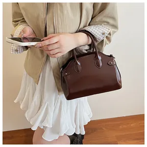 Vue détaillée d'un sac à main en cuir verni marron foncé avec rivets métalliques argentés