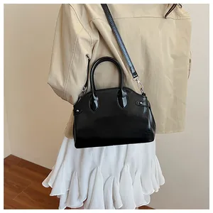 Vue détaillée du sac en cuir verni noir avec bandoulière réglable et poignées rondes