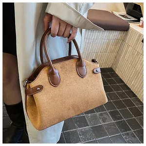 Gros plan d'un sac cabas en daim camel avec garniture en cuir marron et rivets argentés
