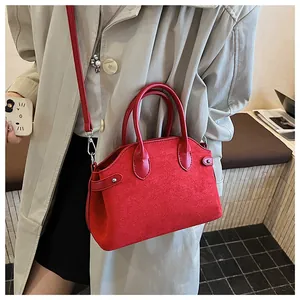 Détail du sac à main rouge en daim porté avec un trench beige pour un style élégant