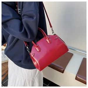 Vue latérale du sac Boston rouge brillant avec détails argentés porté en bandoulière