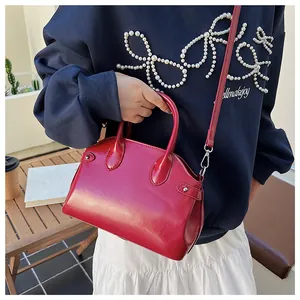 Détail du sac cabas bordeaux en cuir verni avec poignées courbées et bandoulière fine
