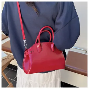 Détail d'un sac à main rouge brillant avec poignées et bandoulière réglable