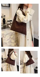 Close-up of brown suede tote bag featuring metallic rivet eyelets and retro biker style