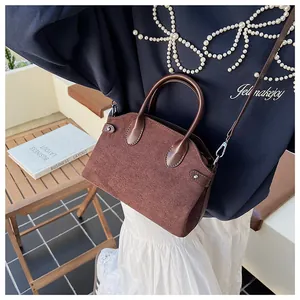 Détail du sac à main en daim marron avec poignées en cuir et rivets métalliques