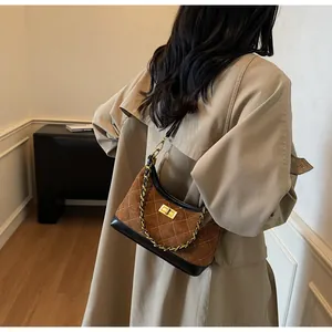 Close-up of brown suede underarm bag with white quilted stitching and chain strap