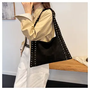 Detail of a large black studded shoulder bag showing the drape and side rivet accents