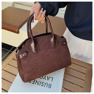 Détail d'un sac à main en daim marron foncé avec fermoir argenté sur bois