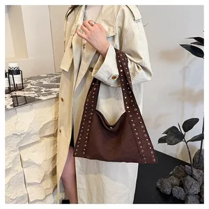 Detail of dark brown suede shoulder bag with gold metal rivet studs on the wide strap