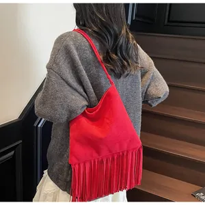 Bolso de ante rojo con flecos largos mostrado por una modelo en una escalera de madera