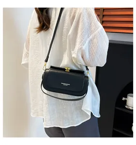 Détail du sac bandoulière en cuir noir avec fermoir doré et lettrage de mode chic