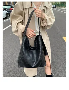 Detailed side view of black woven hobo tote bag on woman in trench coat