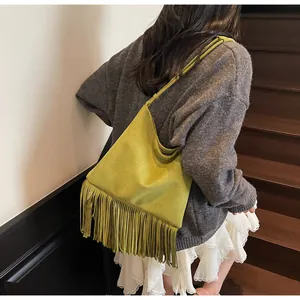 Detalle del bolso tote retro en ante amarillo con flecos largos colgado al hombro