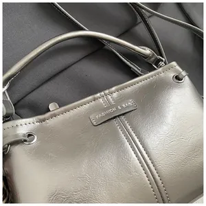 Detail van zilveren crossbodytas met geplooide textuur en modieus logo op het oppervlak