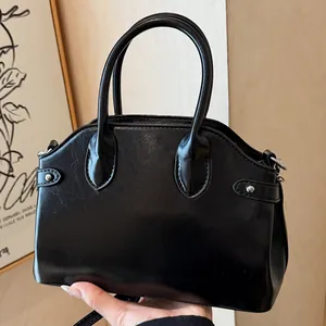 Sac à main en cuir noir brillant avec rivets argentés et poignées arrondies