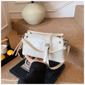 Detail van de gebroken witte leren tas met logo in reliëf en zilverkleurige metalen gesp