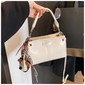 Detail van beige glanzende schoudertas met pluche bedeltje en Fashion & Bag logo
