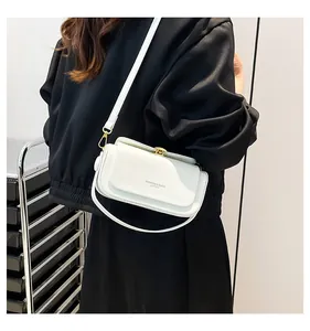 Sac bandoulière minimaliste en cuir blanc porté par un modèle avec fermoir en métal