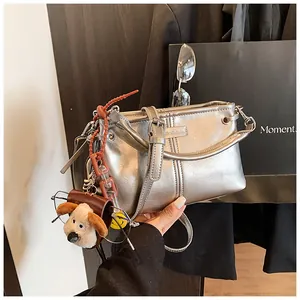 Detail van zilveren metallic handtas met stiksels en een schattige honden hanger