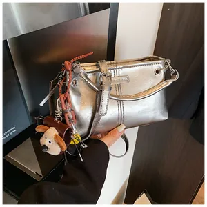 Detail van zilveren metallic draagtas met pluche puppy-bedel en metalen merkplaatje