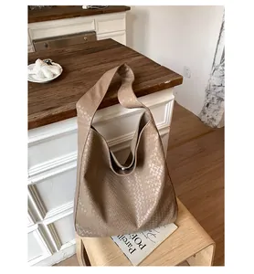 Macro view of woven leather texture and magnetic clasp on this beige hobo tote bag