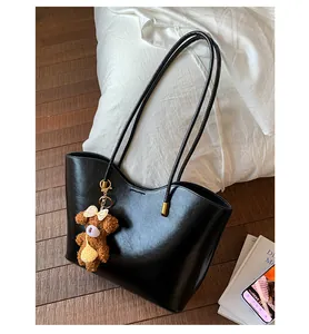 Détail du grand sac cabas noir brillant avec bord ondulé et pendentif ours brun