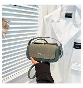 Détail du sac en cuir vert et tissu tissé beige avec fermoir doré et une poignée supérieure