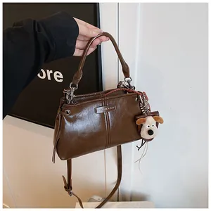 Detail van retro bruine tas met metalen logoplaat en een schattige pluchen hondenhanger