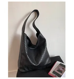 Detailed close-up showing the intricate black quilted woven texture of the large tote bag