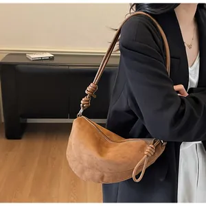 Vue détaillée du sac demi-lune en daim caramel avec une bandoulière décorative à nœuds