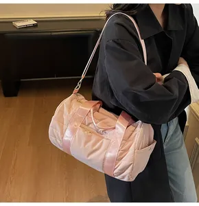 Close-up of pink quilted cylindrical travel bag featuring golden hardware and side pockets