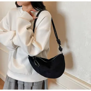 Détail du sac croissant noir avec bandoulière à nœuds décoratifs et texture en daim doux
