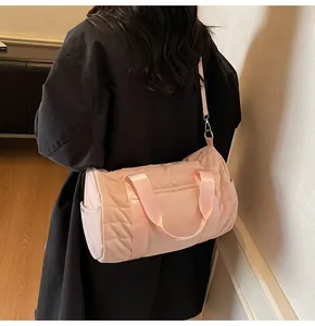 Detailed view of pink quilted cylinder bag with side pocket and adjustable shoulder strap