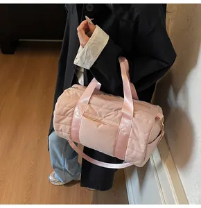 Pink quilted travel duffel bag detail showing water-resistant nylon and wide handle