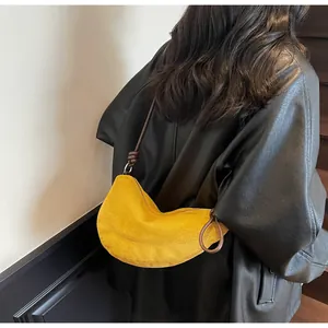 Détail du sac croissant en daim jaune avec bandoulière nouée marron foncé et anneaux