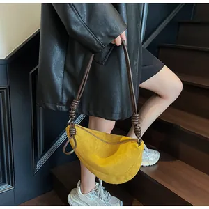Détail d'un sac demi-lune en daim jaune vif avec bandoulière en corde marron tressée