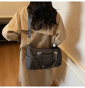 Detail of grey quilted cylinder bag showing side pocket and adjustable nylon strap