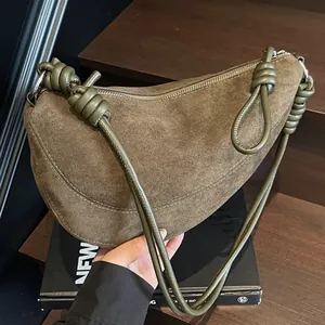 Sac demi-lune rétro en daim vert olive avec sangle nouée sur un escalier en bois