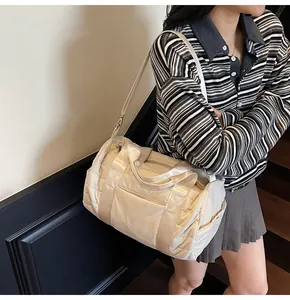 Model wearing a quilted beige duffel bag with a shoulder strap for casual travel use