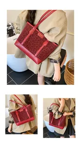 Detail of red leopard print tote bag featuring metallic plaque and leather straps