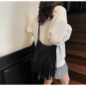 Modèle portant un sac bandoulière bohème noir avec de longues franges et texture suède