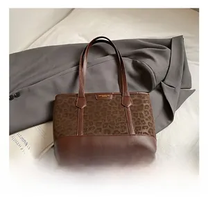 Detail shot of leopard print tote bag featuring a gold metal logo and brown leather accents