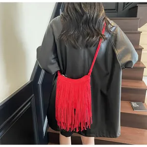 Gros plan sur un sac bandoulière rouge à franges bohèmes sur un escalier en bois