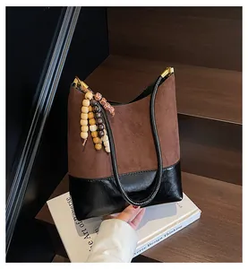 Close-up of retro brown suede tote bag with decorative wooden beads on wooden stairs