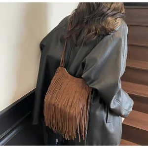 Gros plan d'un sac à bandoulière vintage à franges marron porté avec un manteau en cuir
