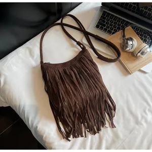 Vue détaillée du sac à bandoulière en daim marron avec franges et accessoires