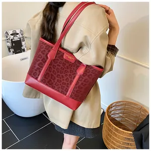 Red leopard print tote bag with long leather handles shown worn on the shoulder