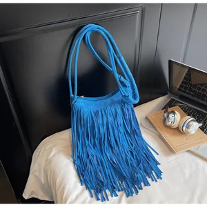 Détail du sac à bandoulière en daim bleu roi à franges avec livres et écouteurs